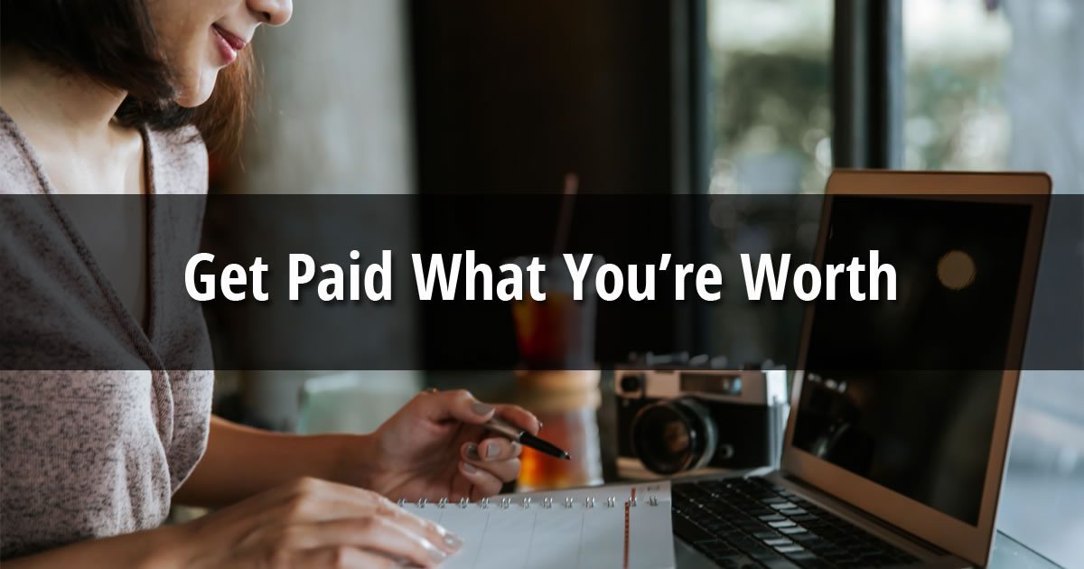Woman sitting in front of laptop writing in notebook